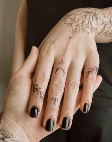 two people with tattoos on their hands holding each other's fingers and looking at the camera