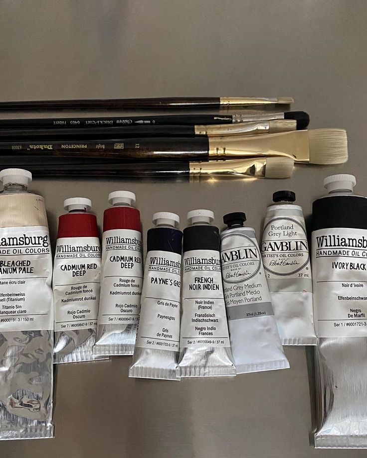 several different types of paint and brushes sitting on a table next to each other,