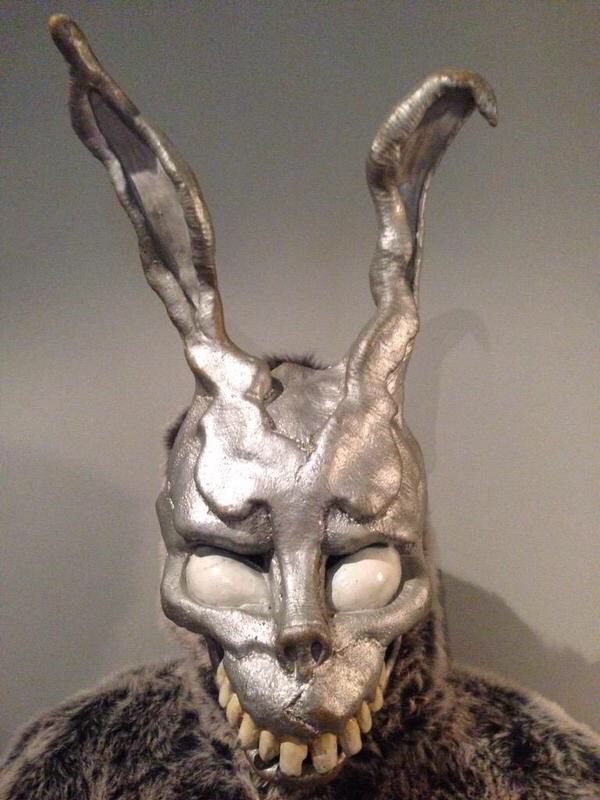 a silver rabbit mask on top of a fur covered head and chest, with white teeth