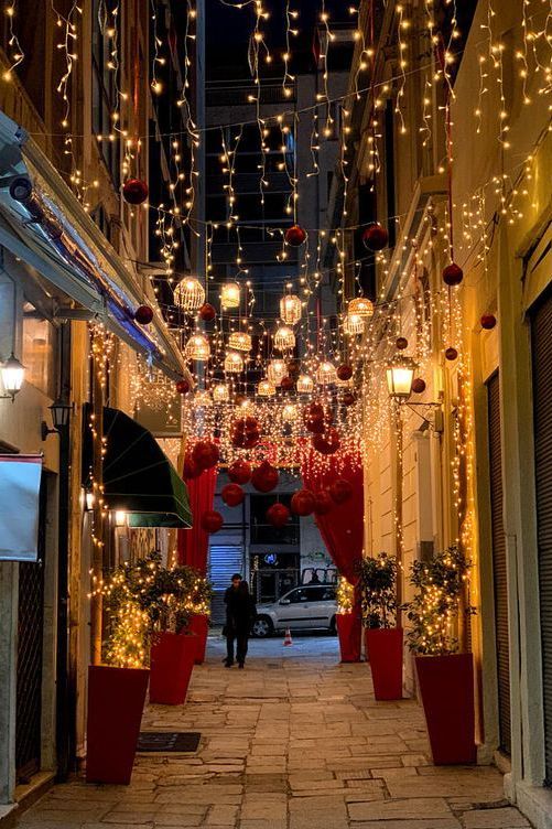 an alley way with lights and potted plants