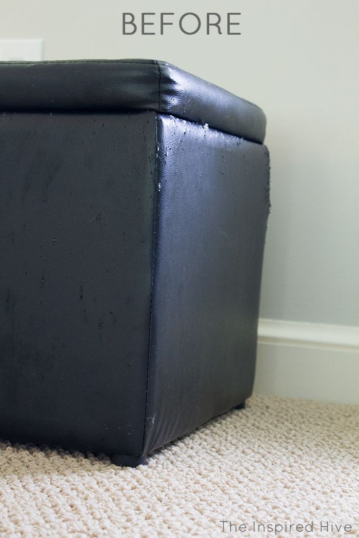 a black leather ottoman sitting on top of a carpeted floor next to a white wall