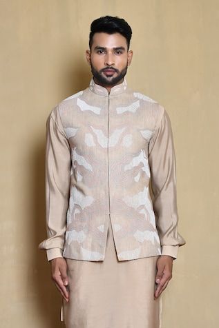 Beige sleeveless bundi in silk base with all over helix swerve thread embroidery. Paired with a plain full sleeves cross cut kurta and golden pant. - Aza Fashions Designer Beige Fitted Nehru Jacket, Fitted Silk Nehru Jacket For Transitional Season, Designer Sleeveless Fitted Bandhgala, Fitted Sleeveless Designer Bandhgala, Fitted Sleeveless Bandhgala For Designer Wear, Transitional Beige Fitted Nehru Jacket, Fitted Sleeveless Bandhgala For Eid, Fitted Sleeveless Nehru Jacket For Transitional Seasons, Elegant Sleeveless Nehru Jacket For Transitional Season