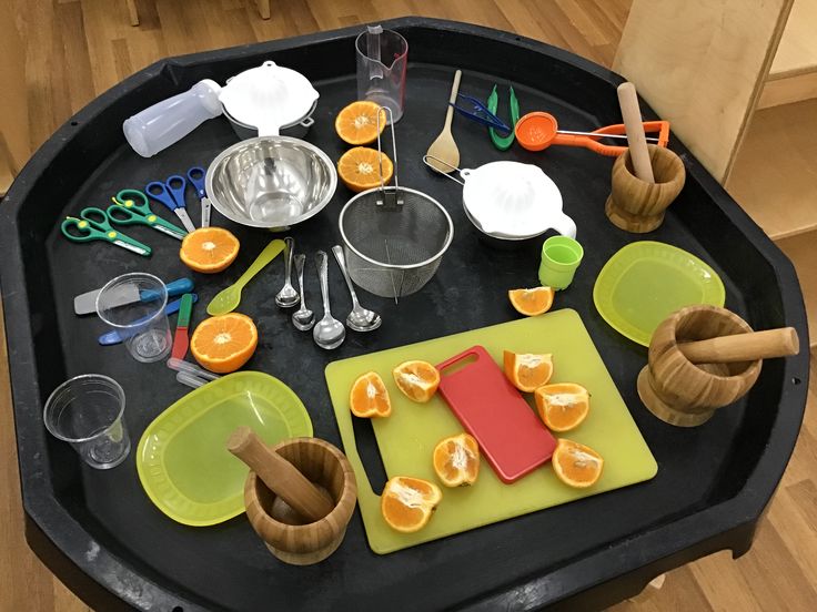 an assortment of kitchen utensils are laid out on a black tray with orange slices