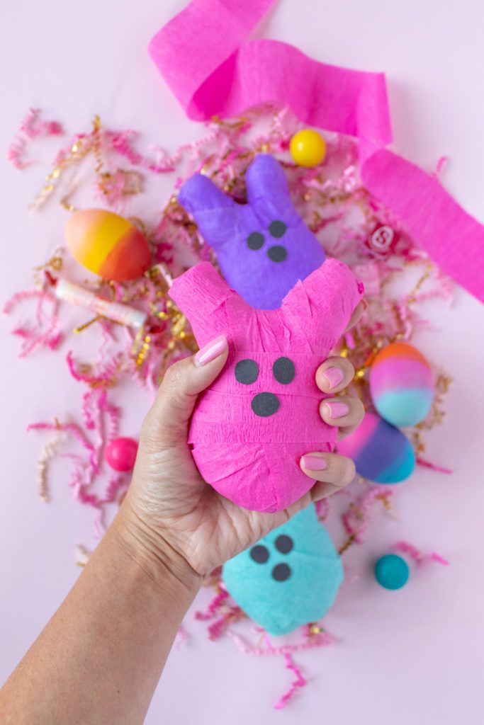 a person holding up a pink and purple stuffed animal in front of confetti sprinkles