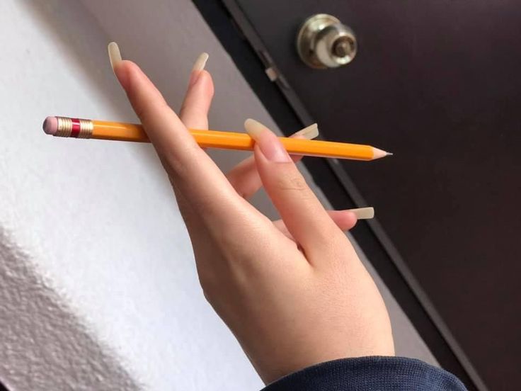 a person holding two pencils in their hand and pointing them to the left side