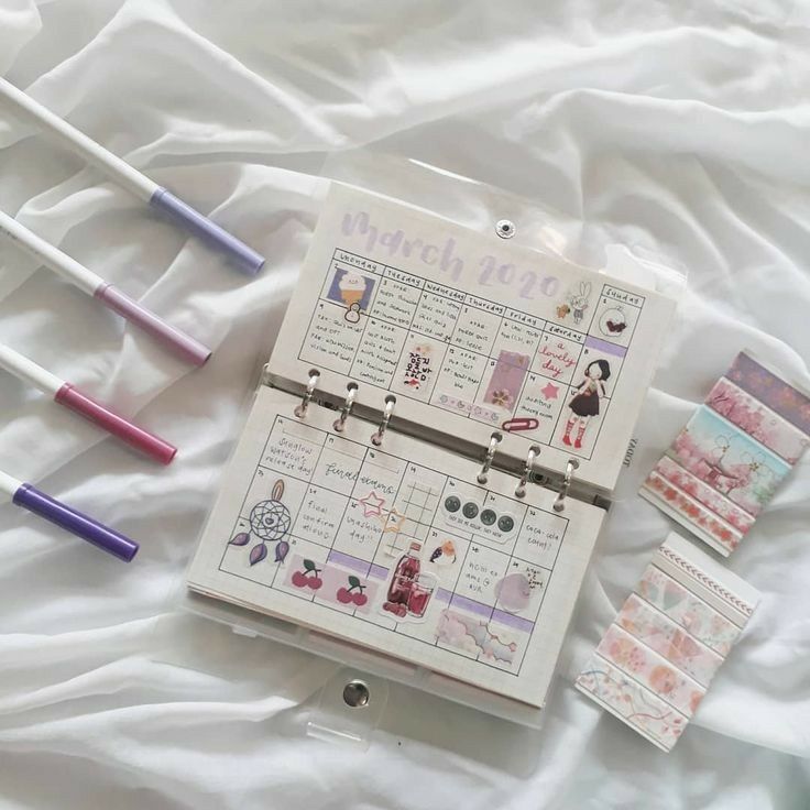 a calendar and some stickers laying on a bed with white sheets, next to each other