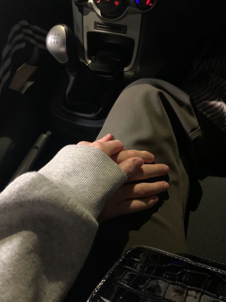 two people holding hands while sitting in a car