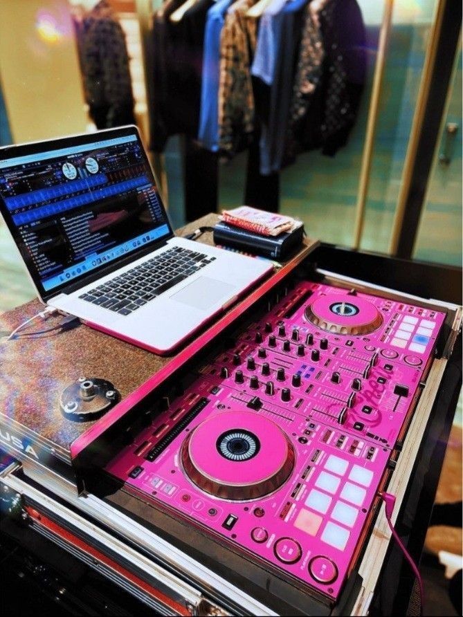 a laptop computer sitting on top of a pink dj's mixer and turntable