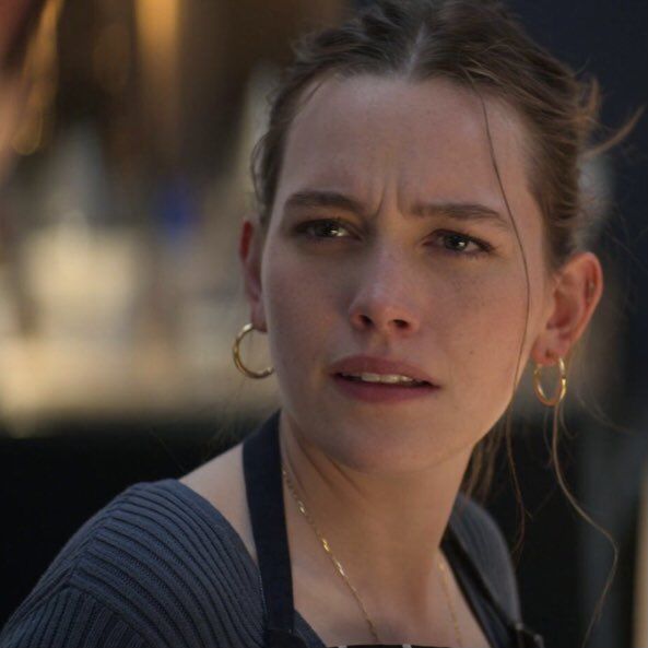 a close up of a person wearing earrings and looking at the camera with a serious look on her face