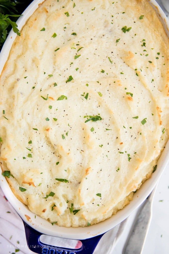 a casserole dish with cheese and parsley on top, ready to be eaten