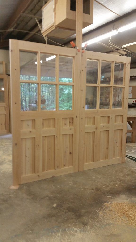 the inside of a garage with wooden doors and windows on each side, surrounded by plywood planks