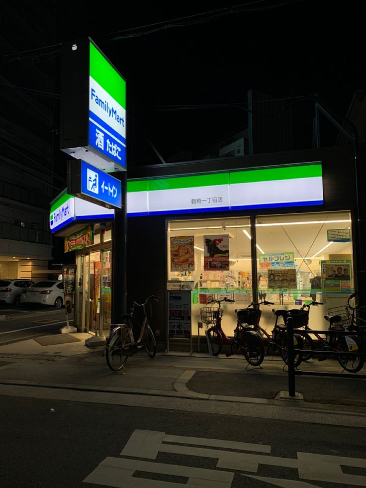 an empty gas station at night with bikes parked outside the store front and signs on the side of the building