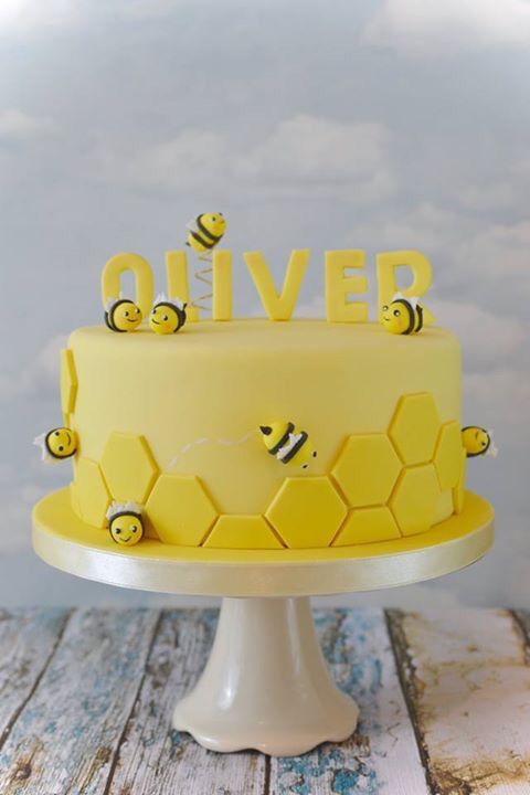 a yellow cake with bees on it and the word'deliver'spelled in honeycombs