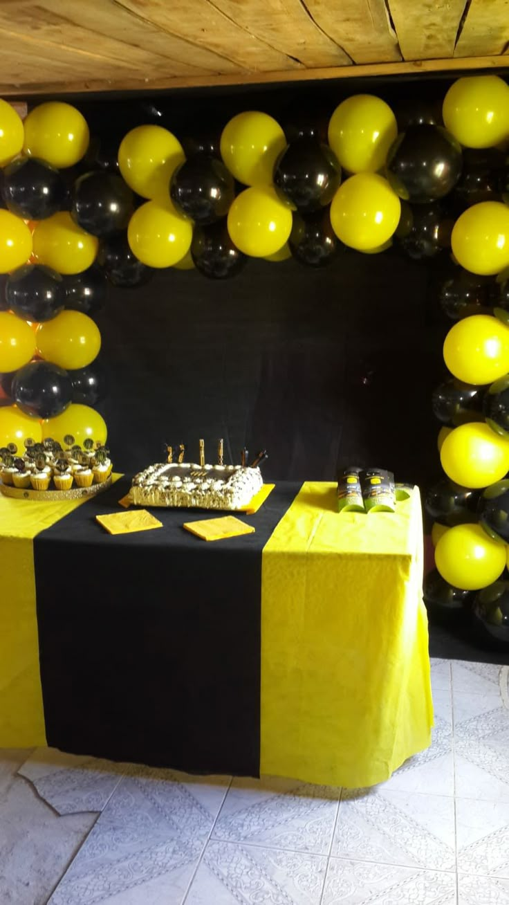 a table with black and yellow balloons on it