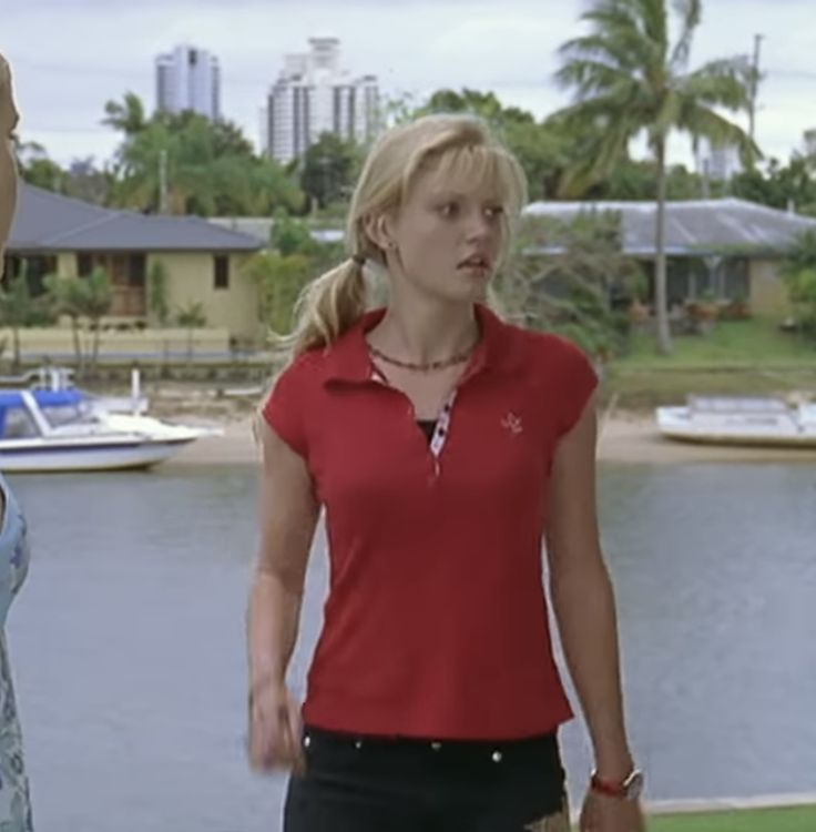 two women standing next to each other in front of a body of water and palm trees