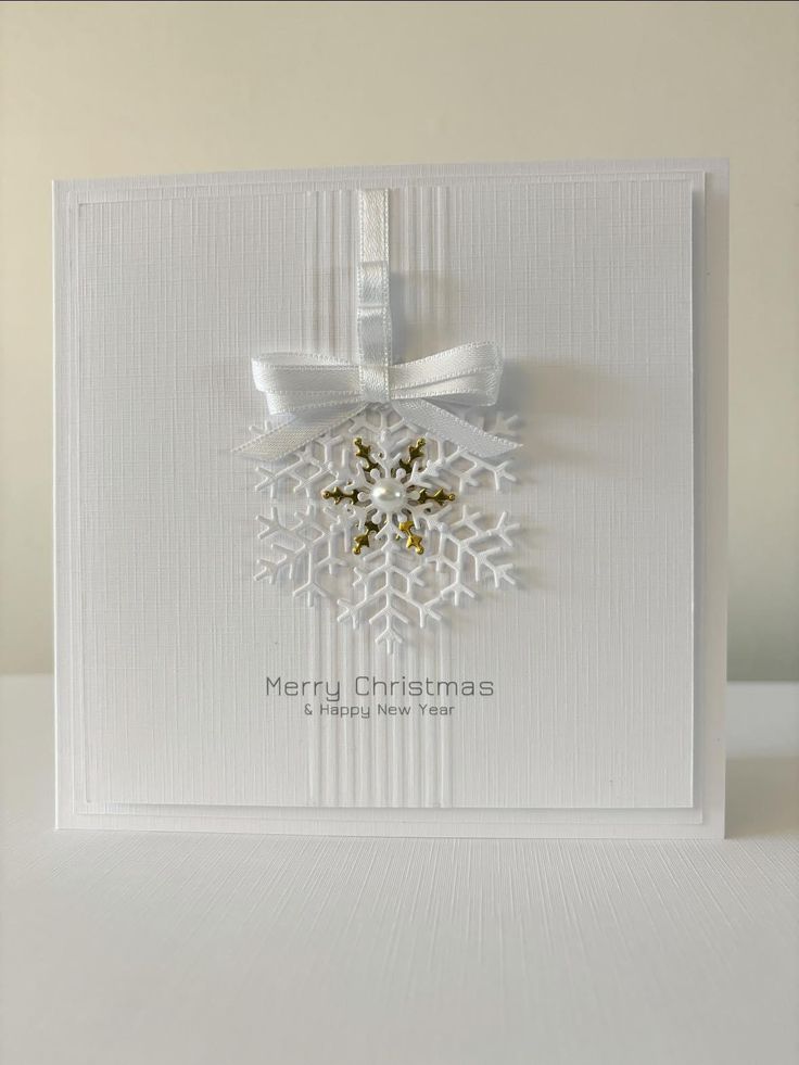 a white christmas card with a snowflake on the front and ribbon around it