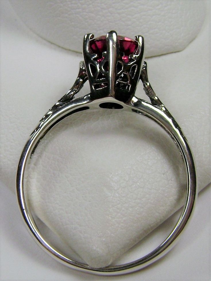 Simulated Red Ruby Ring Wedding #D22 This is a Victorian Era solitaire ring. This lovely sterling silver wedding solitaire has an approximately .5 carat simulated red ruby gemstone. This full cut flawless gemstone is 6mm (1/4") in diameter. The inside of the band is marked 925 for sterling silver. Notice the beautiful crown design of the silver filigree setting and the etched band. This is a lovely rendition of an Antique filigree ring. Classically fashioned, this ring is a vintage wedding style Red Ruby Ring, Antique Filigree, Victorian Wedding, Crown Design, Vintage Style Wedding, Filigree Ring, Ruby Gemstone, Red Ruby, Engraved Items