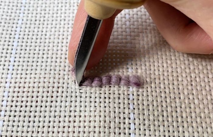 a person is using a small pair of scissors to cut fabric with needle tip and thread