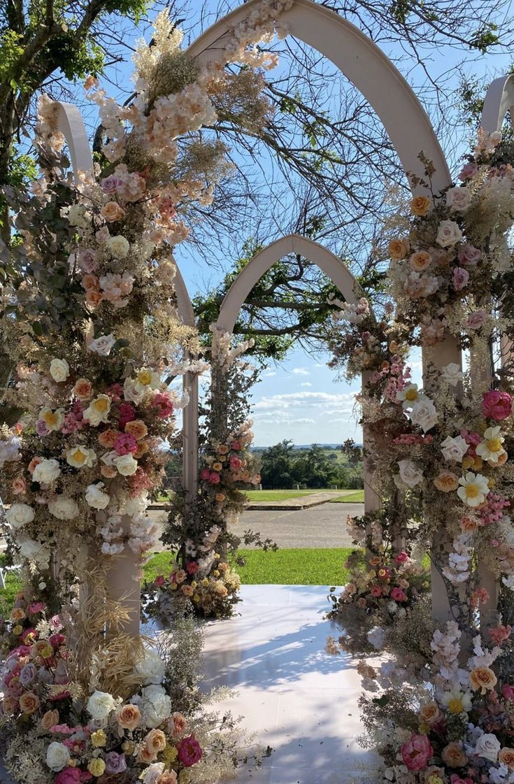 an outdoor ceremony with flowers and arches