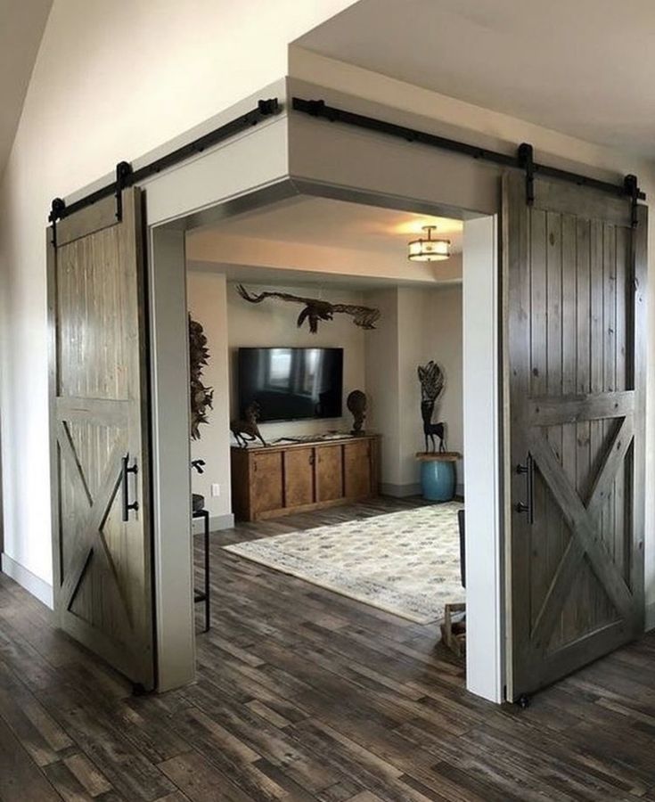 an open barn door leading to a living room with a television on the far wall