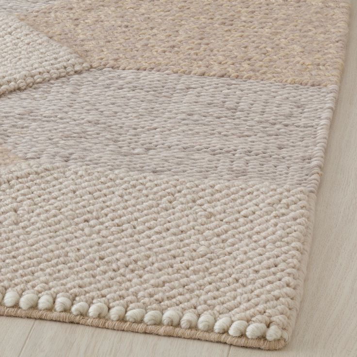 an area rug with white and beige colors on top of a wood flooring surface