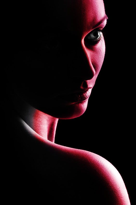 a woman's face is shown in the dark with red light coming from her eyes