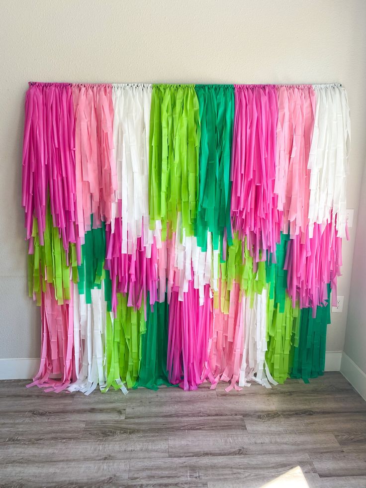 colorful streamers hanging on the wall in front of a white wall with wood flooring