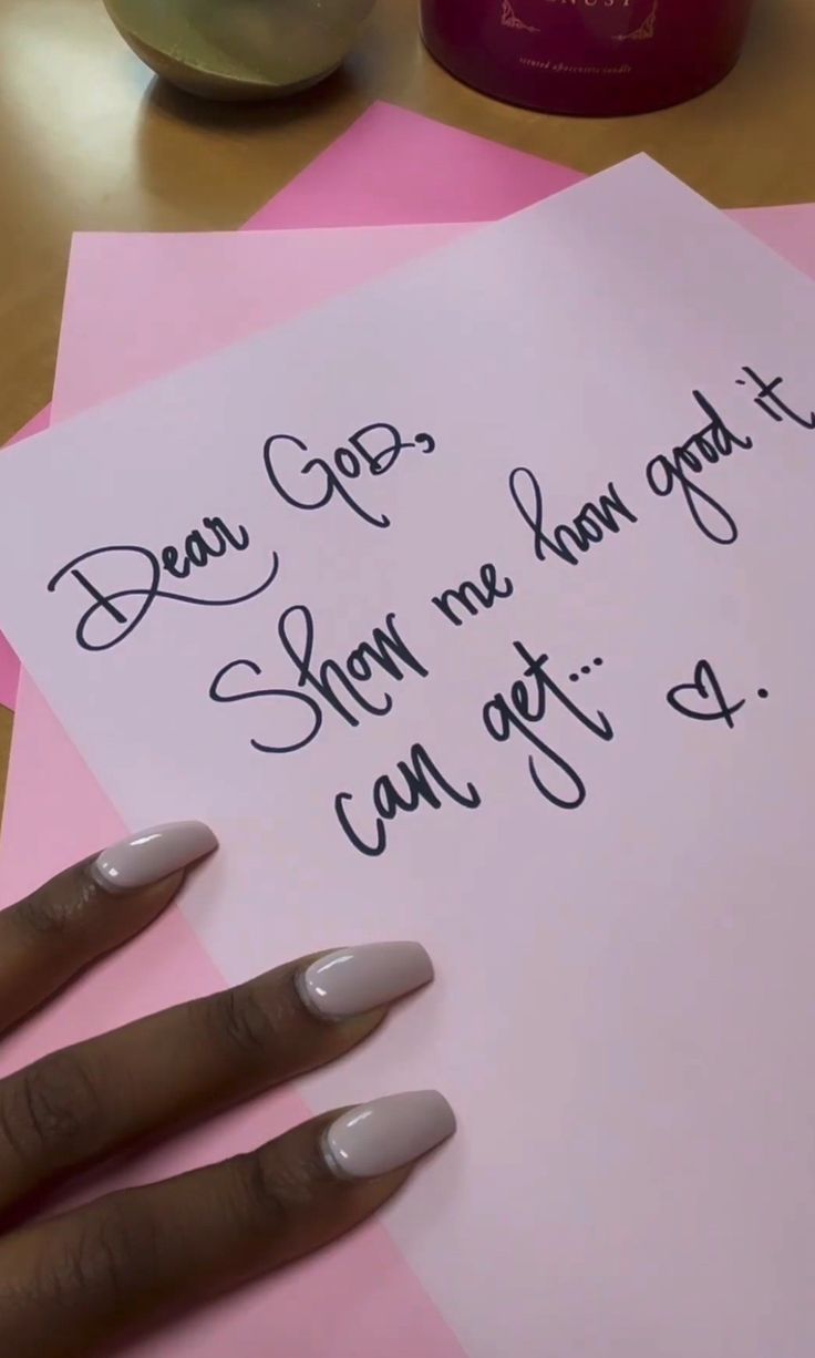 a woman's hand on top of two pink and white papers with writing on them