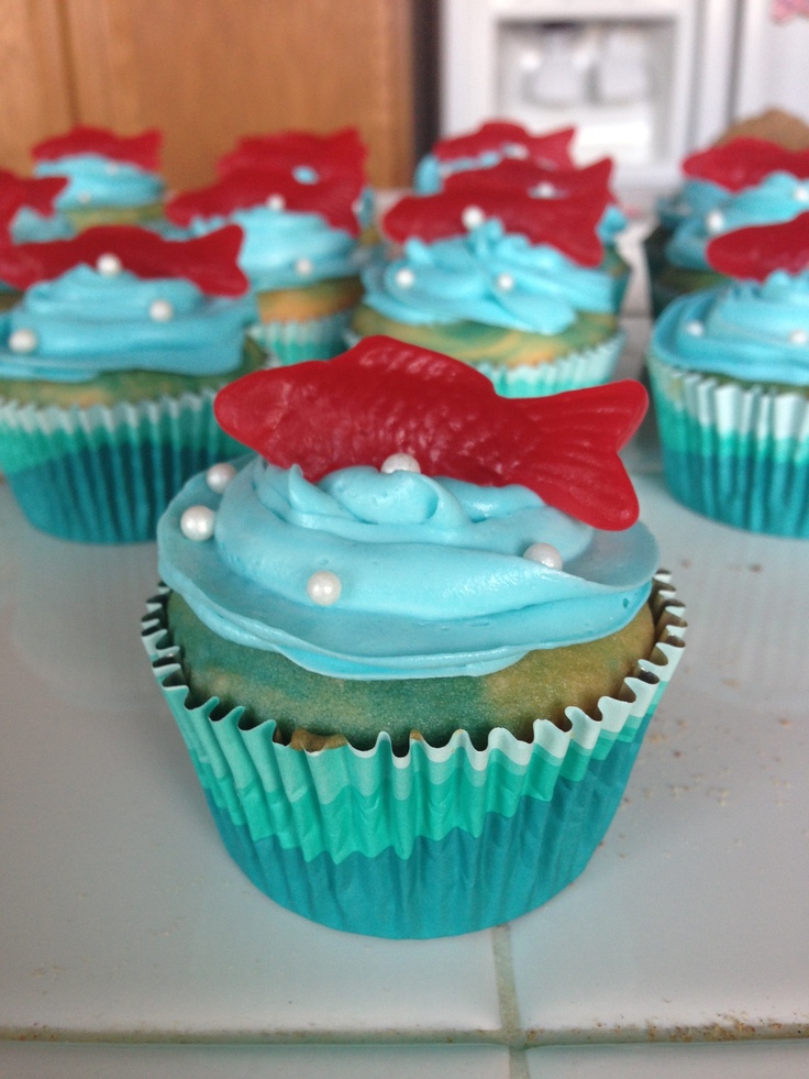 cupcakes with blue frosting and red bows on them sitting on a counter