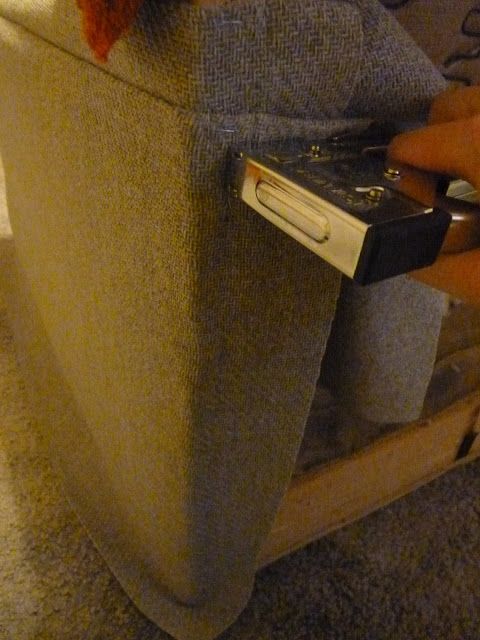 a person holding a remote control in front of a couch with the arm rest down