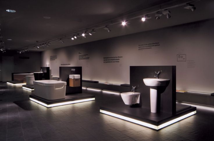 a room filled with different types of sinks and bathtubs on display in the dark