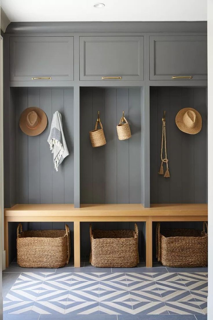 a bench with baskets and hats on it in front of some gray cupboards filled with hats