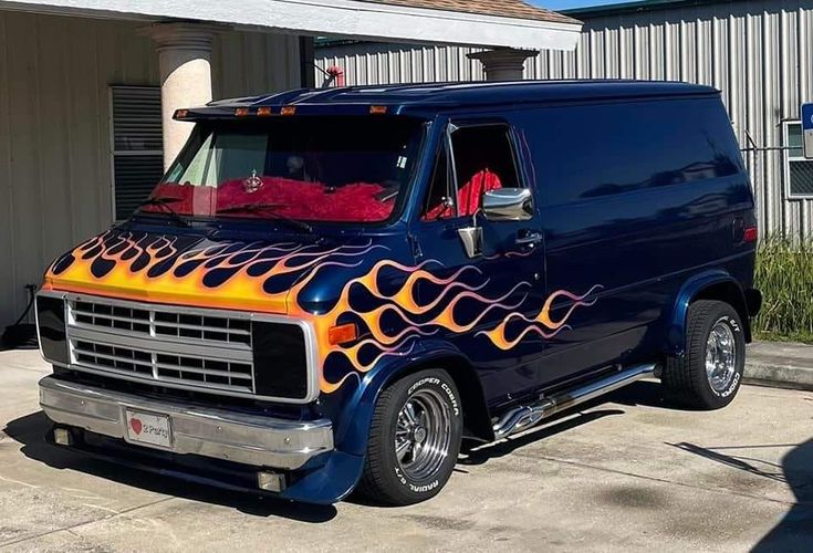 a blue van with flames painted on it's side parked in front of a building