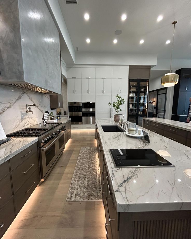 a large kitchen with marble counter tops and stainless steel ovens, stove hoods, and cabinets