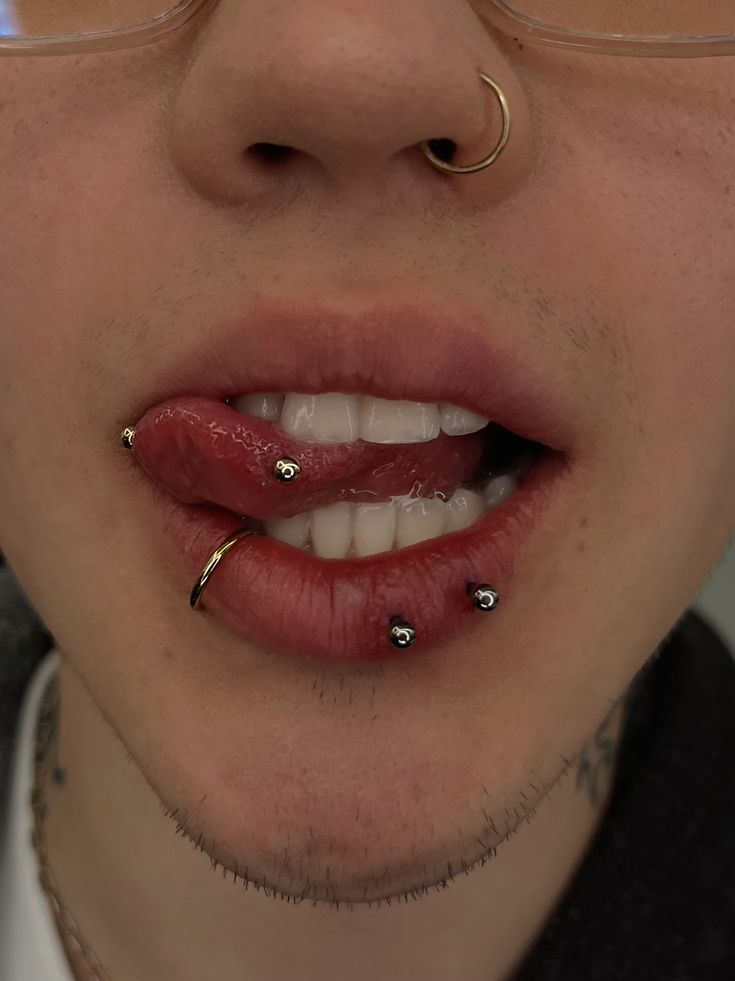 a man with piercings on his tongue and nose is looking at the camera while wearing glasses