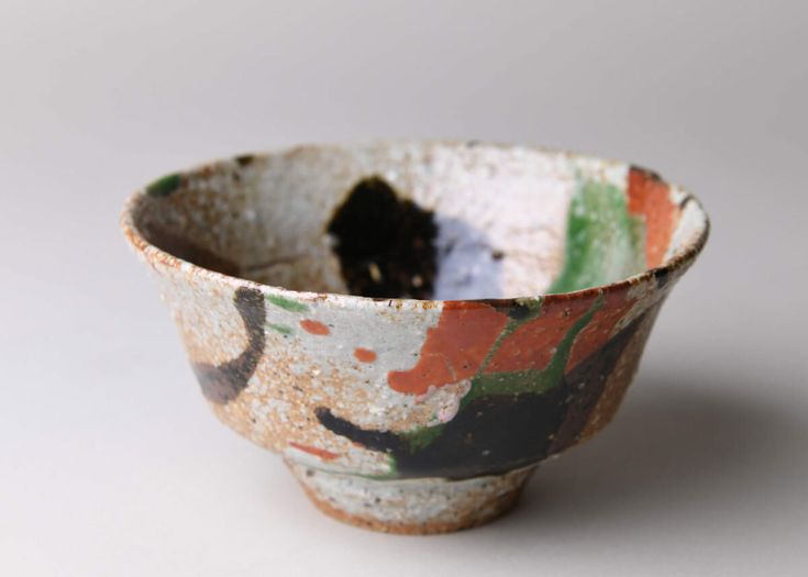 a small bowl is sitting on a white surface with black and orange designs in it