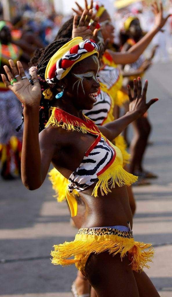 a group of women in costume dancing on the street with their hands up and eyes closed