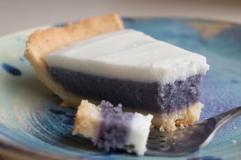 a piece of blueberry pie on a plate with a fork and crackers next to it