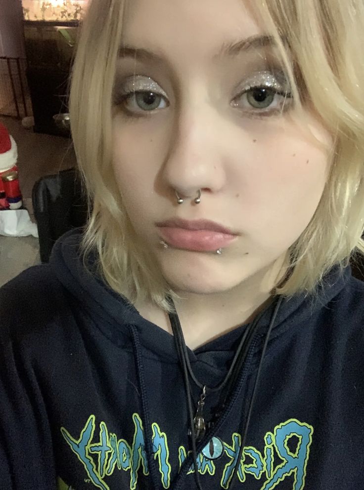 a girl with piercings on her nose is looking at the camera while wearing a black hoodie