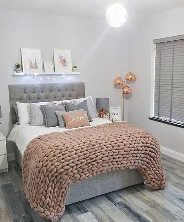 a bedroom with white walls and wood flooring is decorated in pink, grey and gold