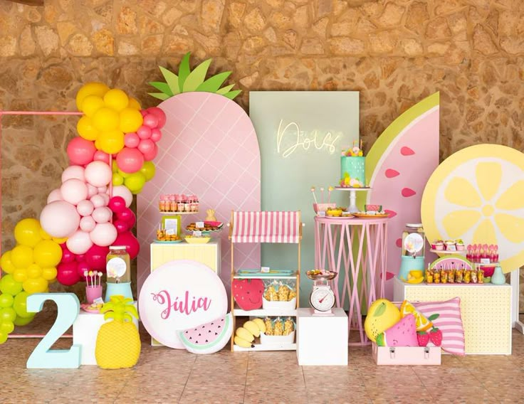 a table with pineapples, watermelon balloons and other items on it