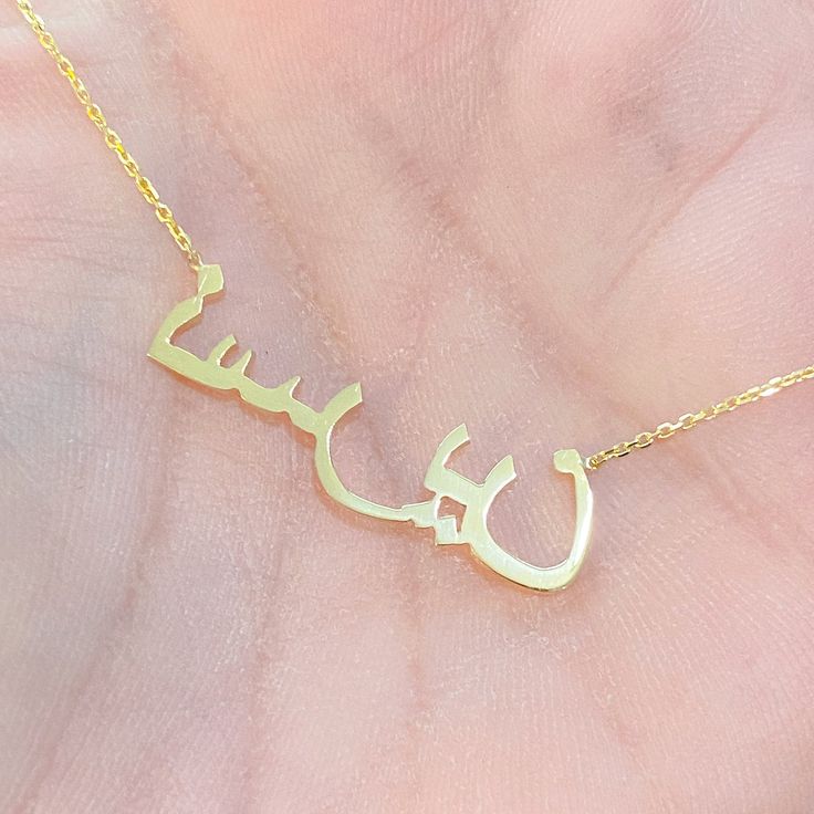 "This unique personalized single name cut-out necklace is composed of 14K solid gold and beautifully complemented by a durable 14K solid gold adjustable chain. This design is also available to be purchased as a charm alone without the chain. NOTE: Kindly indicate the language desired (i.e. Hebrew, Farsi, or Arabic) in the \"Notes\" section upon checkout. ♦Name Dimensions: approximately 7mm high x width depending on the names desired ♦ Pendant Thickness: approximately 1mm ♦ Metal Finish: High Shi Customized 14k White Gold Necklace, 14k Gold Name Necklace With Round Pendant, Yellow Gold Round Pendant Necklace With Name, Yellow Gold Name Necklace With Round Pendant, Customized Yellow Gold Pendant Necklace, Customized Yellow Gold Plated Name Necklace, Custom Name Necklace In Gold Plated Yellow Gold, Custom Name Necklace In Yellow Gold Plated, Custom Gold Plated Yellow Gold Necklace With Name