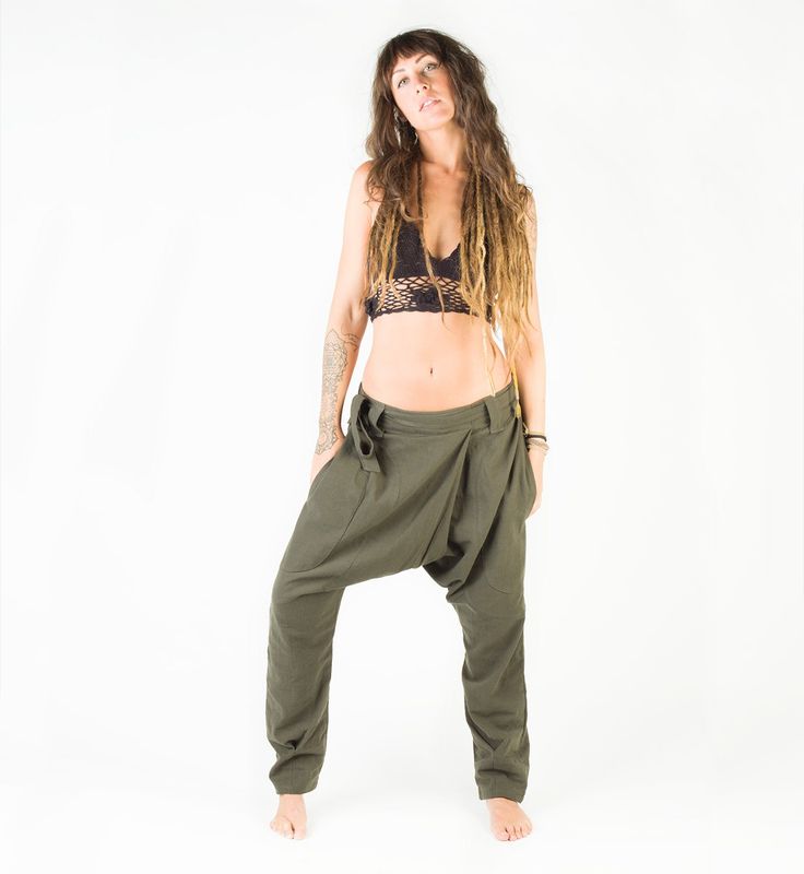 a woman with dreadlocks standing in front of a white background wearing green pants