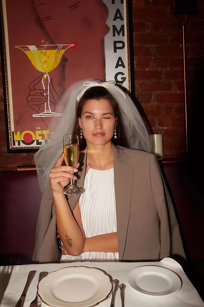 a woman sitting at a table with a glass of wine in front of her face