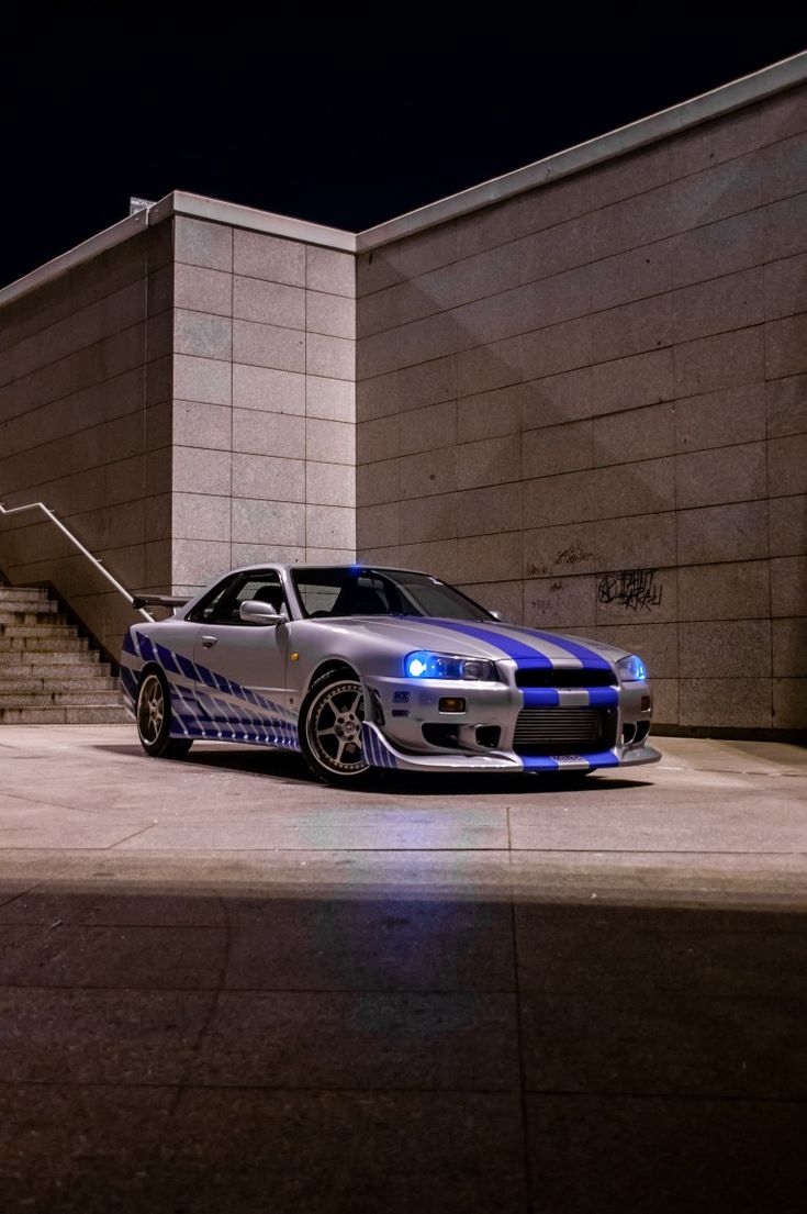 a blue and white car parked in front of a building with stairs leading up to it