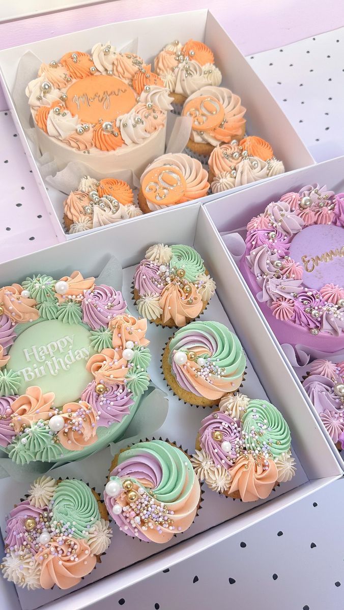 two boxes filled with colorful cupcakes on top of a table