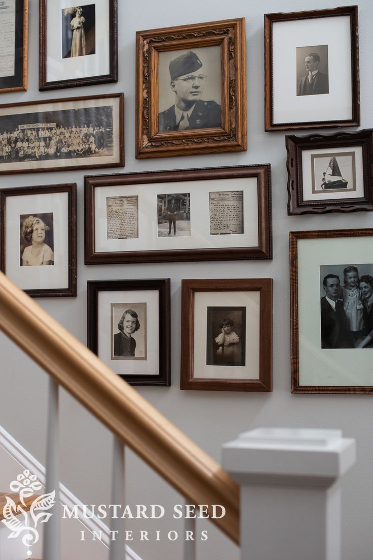 many framed photographs are hanging on the wall next to a banister and stair case