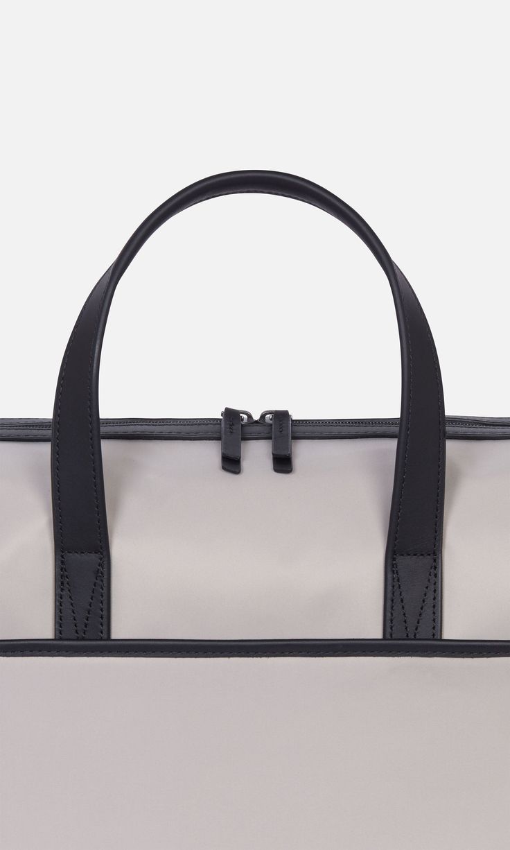 Designed to be the perfect piece of hand luggage, our overnight bag will sit neatly under the seat in front of you on a plane, and has a back sleeve to slot over a suitcase handle. It doubles up as an ideal gym bag and comes with a detachable shoulder strap (you'll find this inside a pocket on arrival). Inside, there are plenty of slip pockets including one for a laptop. This holdall is finished with premium leather details. Durable nylon Water-resistant Fits a laptop up to 13” Dimensions 16.34 Modern Travel Bag With Adjustable Handle, Modern Travel Satchel With Adjustable Handle, Modern Satchel With Adjustable Handle For Travel, On-the-go Travel Bag Satchel With Adjustable Handle, Travel Bag With Adjustable Double Handle, Classic Nylon Travel Bag With Luggage Sleeve, Travel Weekender Tote With Adjustable Handle, Travel Weekender Bag With Adjustable Handle, Adjustable Handle Tote Weekender Bag For Travel