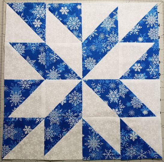 four blocks of blue and white snowflakes are arranged on a green cutting board