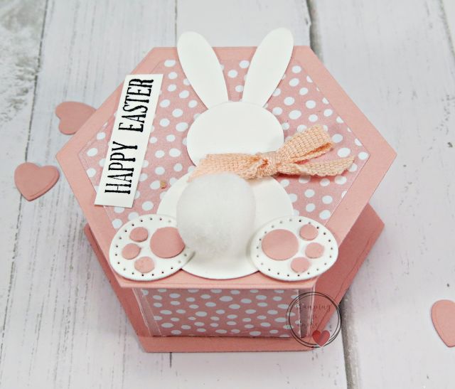 a pink box with white polka dots and an easter bunny on the inside, sitting on a wooden floor